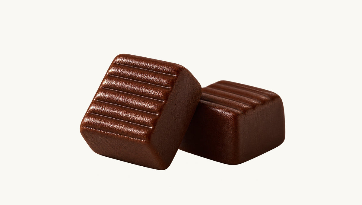 Ilustração editorial de dois caramelos de brigadeiro com estrias na superfície