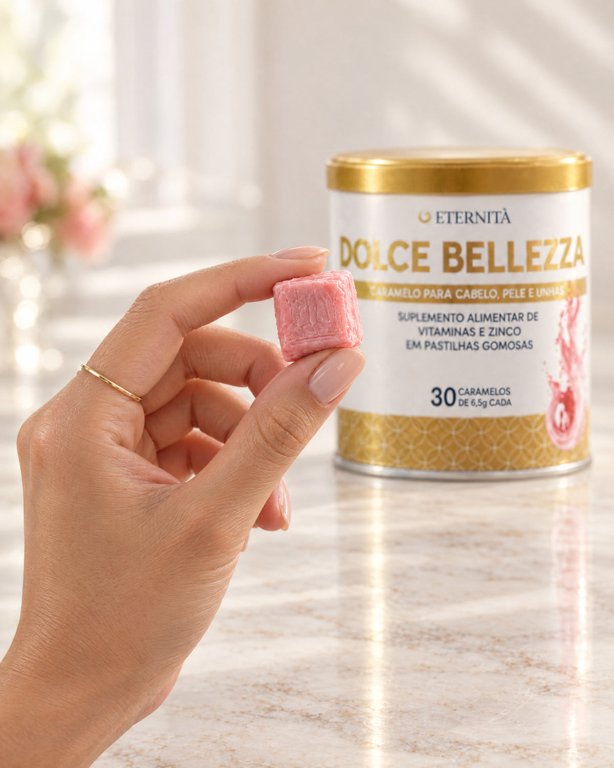 Mão segurando um caramelo Dolce Bellezza sabor morango, com o pote ao fundo