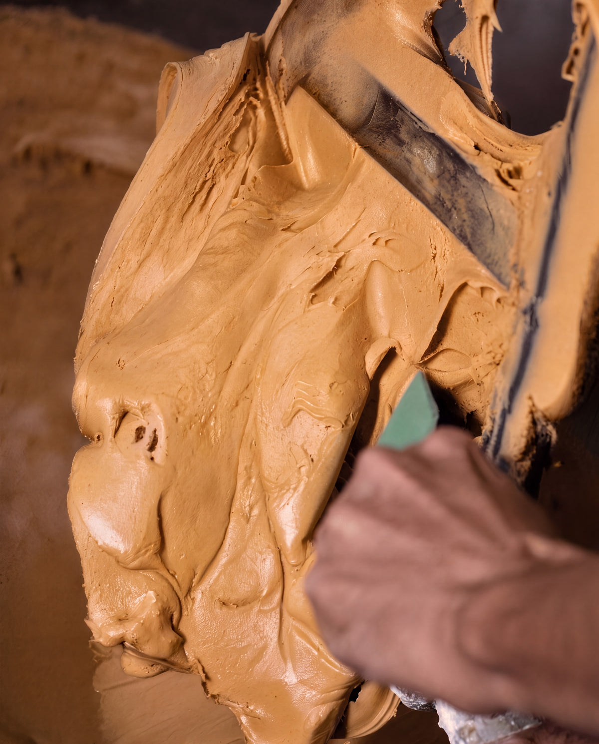 Massa de caramelo sendo raspada à mão no tacho da produção