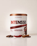 Ímpeto Intensse da Eternità: lata branca de cappuccino com pimenta, ao lado de grãos de café, pimenta, canela em pau e nibs de cacau